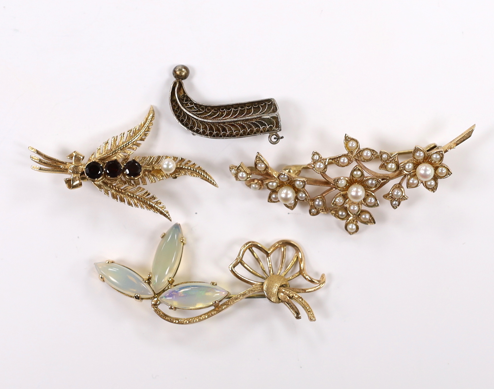 Three assorted modern 9ct and gem set foliate brooches, including garnet, seed pearl and jelly opal, largest 54mm, gross weight 16.4 grams and a white metal filigree brooch.